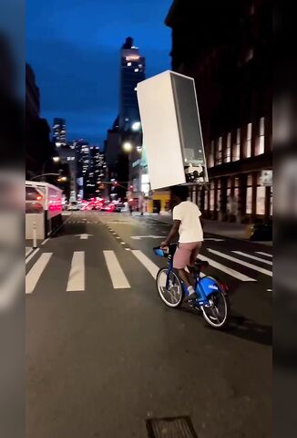 Random Dude On A Bicycle Carrying A Fridge Freezer On His Head